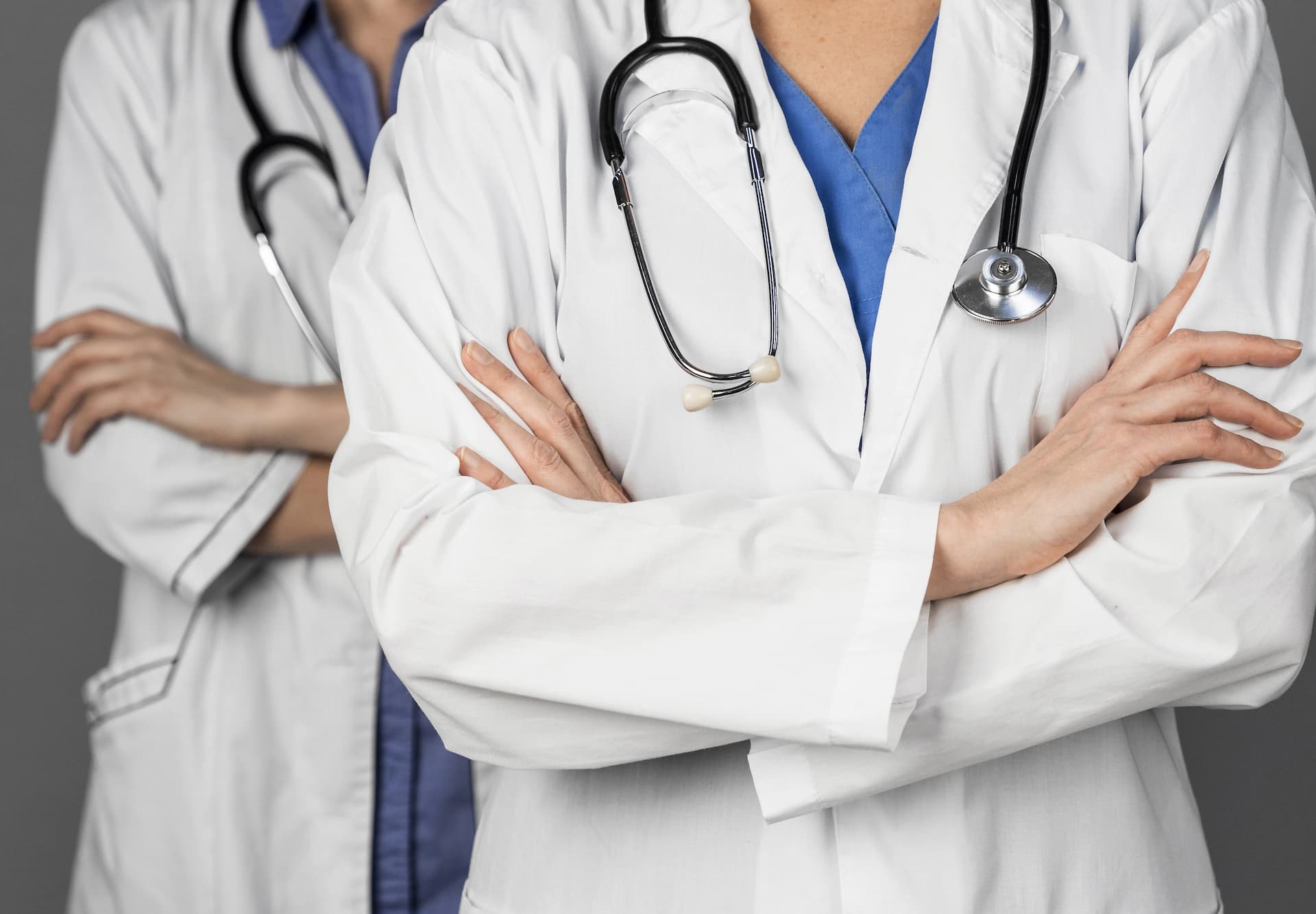 Two doctors in white coats stand with their arms crossed.