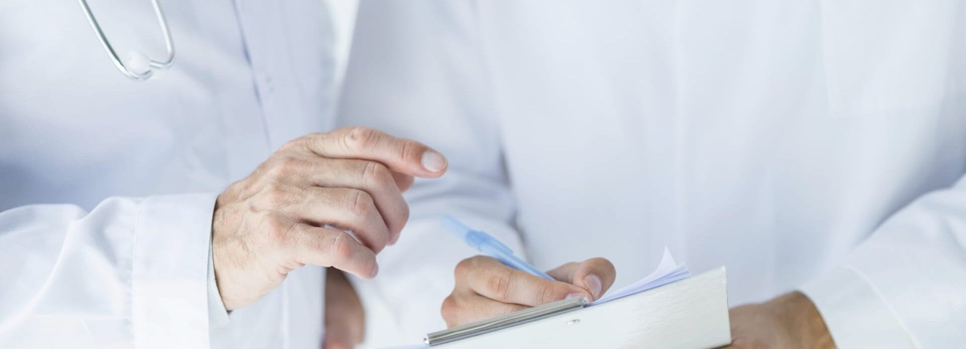 A close-up of two doctors in white coats reviewing a patient's chart on a clipboard.